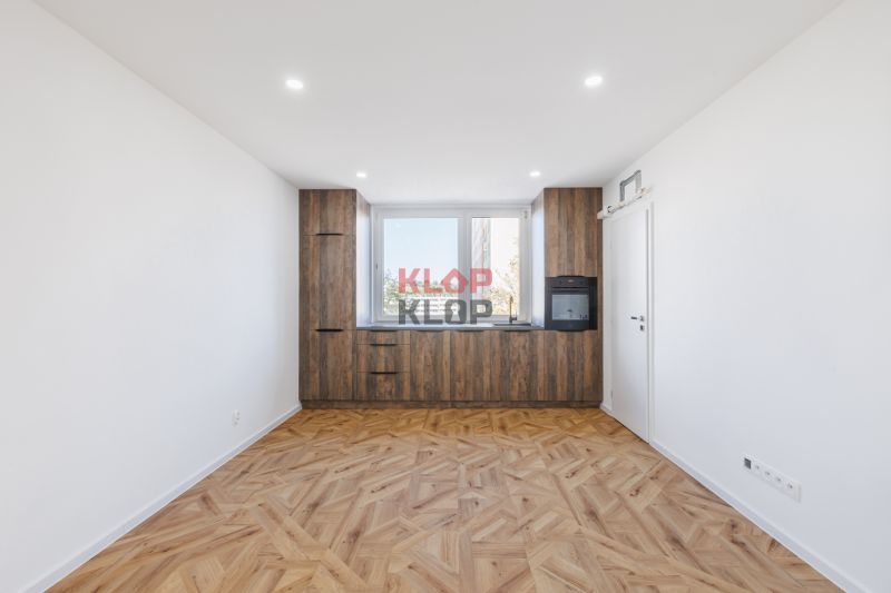 Küche mit Holzboden und eingebauten Geräten in einer 2-Zimmer-Wohnung.