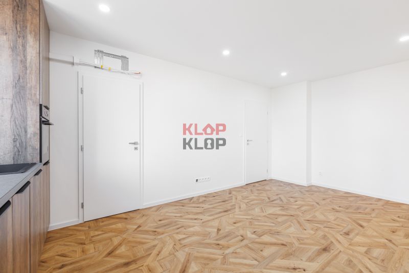 Innenraum einer 2-Zimmer-Wohnung mit Holzboden und eingebauter Küche.
