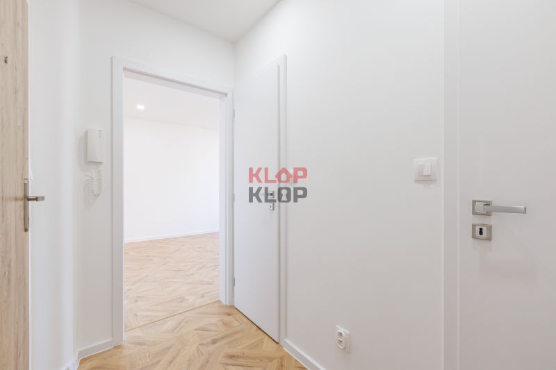 Der Flur in einer 2-Zimmer-Wohnung mit einem Boden in Holzoptik und weißen Wänden.