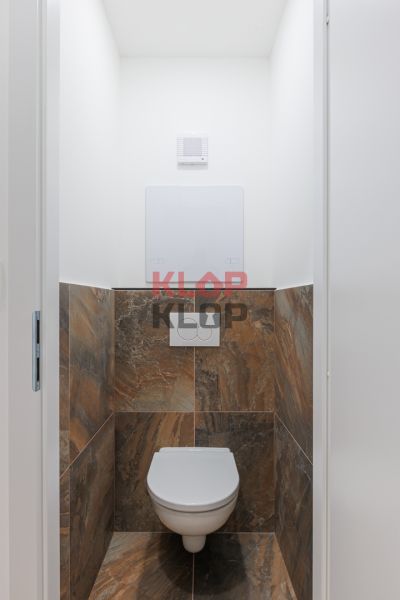 Toilette mit braunen Fliesen in einer 2-Zimmer-Wohnung.