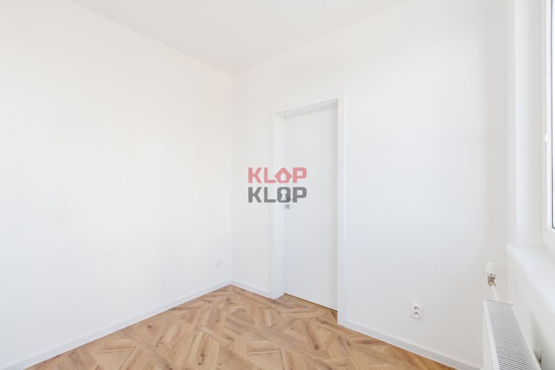 Ein Zimmer mit weißen Wänden und einem Boden in Holzoptik, eine 2-Zimmer-Wohnung.