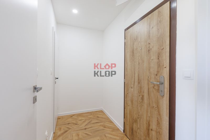 Eingangsflur einer 2-Zimmer-Wohnung mit Holzboden und Holztüren.