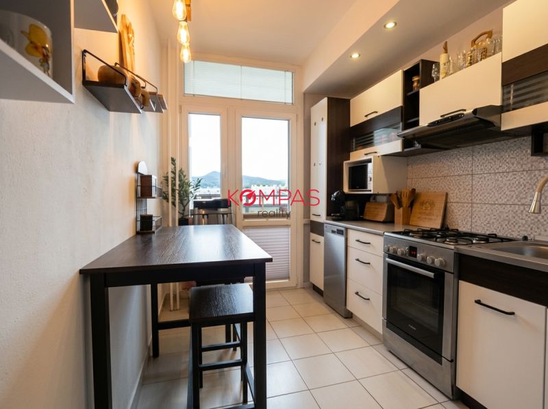 Küche in einer 2-Zimmer-Wohnung mit dunklem Tisch und hellem Boden.