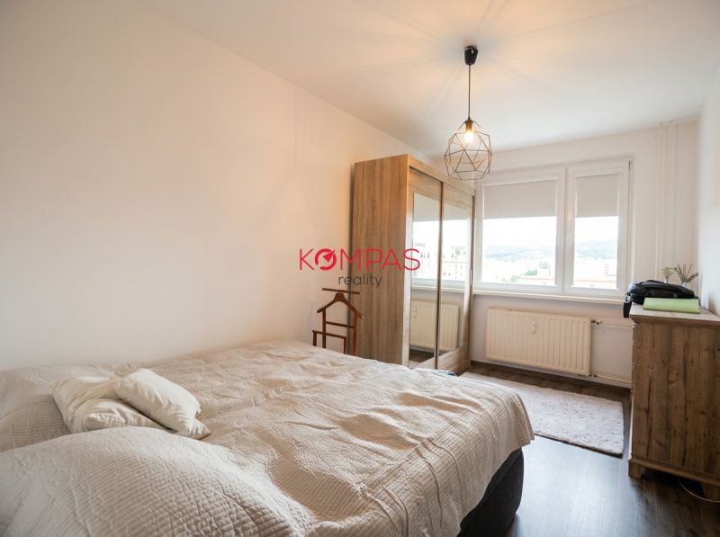 Helles Schlafzimmer mit Schrank, Bett und Boden mit Holzdekor in einer 2-Zimmer-Wohnung.