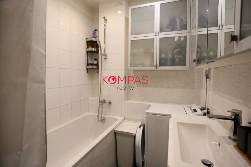 Badezimmer in einer 2-Zimmer-Wohnung mit Badewanne, Schränken und Waschmaschine.