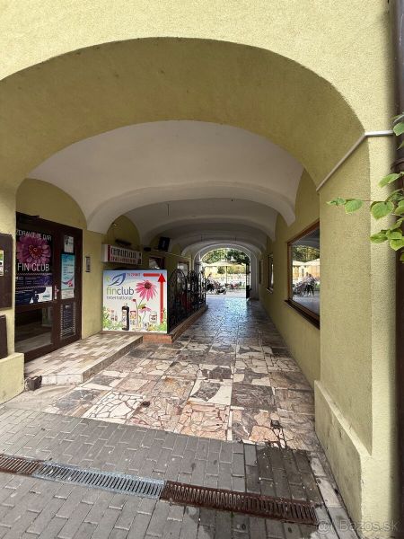 Gewölbter Durchgang, der zu den Gastronomiebereichen in Topoľčany mit Steinpflaster führt.