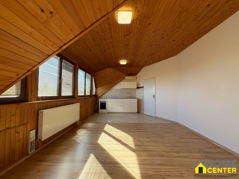 Dachbodenraum in einer 3-Zimmer-Wohnung mit Küchenzeile und Holzboden.