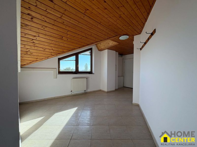 Ein Dachzimmer in einer 3-Zimmer-Wohnung mit einer Holzdecke und Fliesenboden.