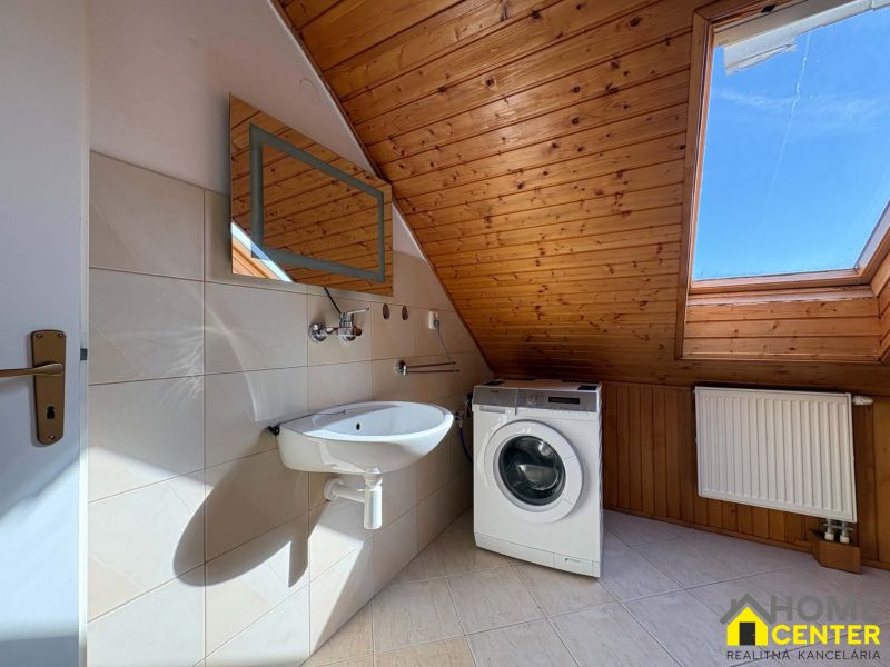 Badezimmer mit Waschmaschine, Waschbecken, Boden mit Holzdekor, Dachfenster.