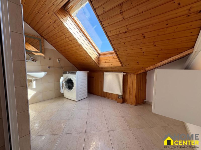 Dachboden-Badezimmer mit Waschmaschine, Dachfenster, Keramikfliesen und Holzverkleidung.