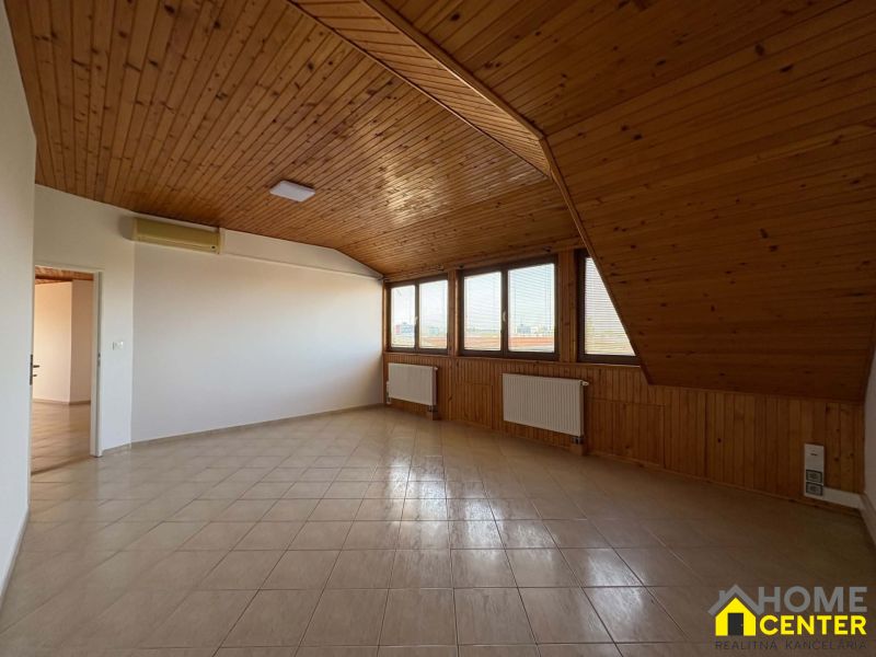 Ein Dachzimmer in einer 3-Zimmer-Wohnung mit Holzverkleidung und Fliesenboden.