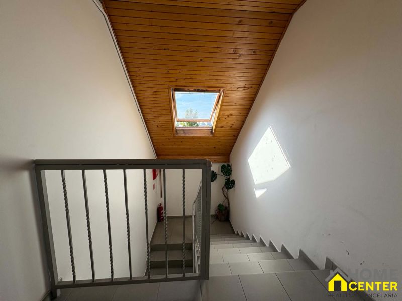 Eine Treppe mit Holzdecke und Dachfenster in einer 3-Zimmer-Wohnung.
