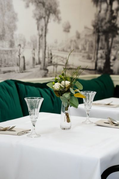 Ein elegant gedeckter Tisch mit einem weißen Tischtuch, einer Vase mit Blumen und Kristallgläsern.