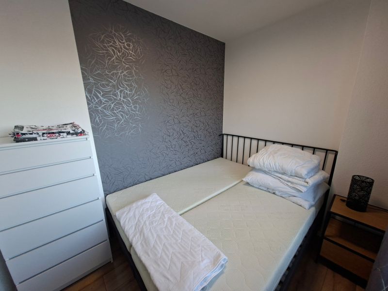Schlafzimmer in einer Einzimmerwohnung mit dunkler Wand und Boden in Holzoptik.