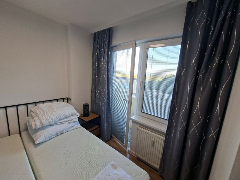 Schlafbereich in einer Einzimmerwohnung mit Vorhängen und einem Fenster mit Aussicht.