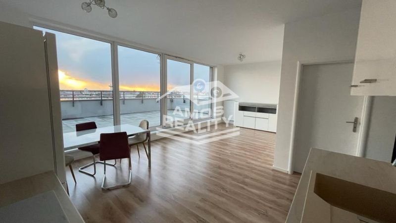 Wohnzimmer mit Esstisch, großen Fenstern und Holzboden.