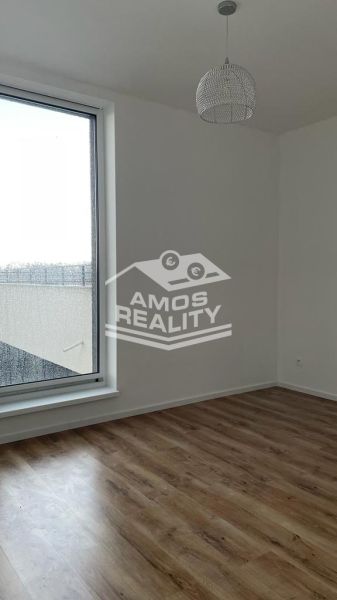 Ein Zimmer in einer 2-Zimmer-Wohnung mit einem großen Fenster und einem Boden in Holzoptik.