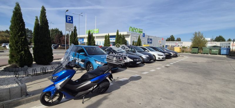 Parkplatz mit Autos und einem Motorrad beim Einkaufszentrum in Malacky in der Javorová-Straße.