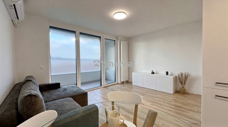 Helles Wohnzimmer mit Sofa, Balkon und Holzdekorboden in einer 2-Zimmer-Wohnung.