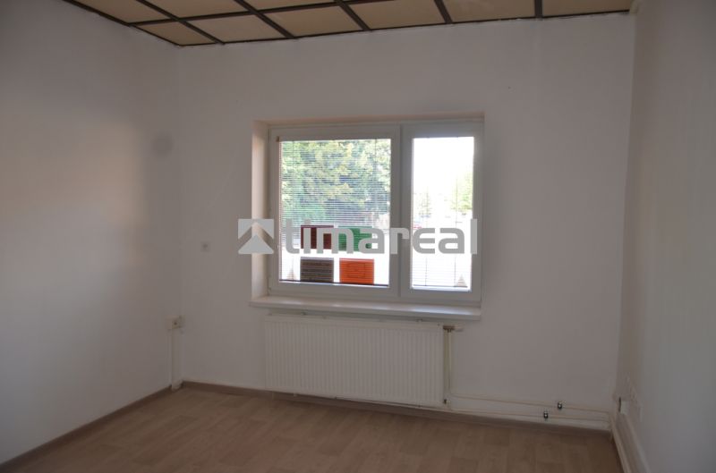 Büros mit weißen Wänden und einem Boden in Holzoptik, ein Fenster mit Heizkörper ist zu sehen.