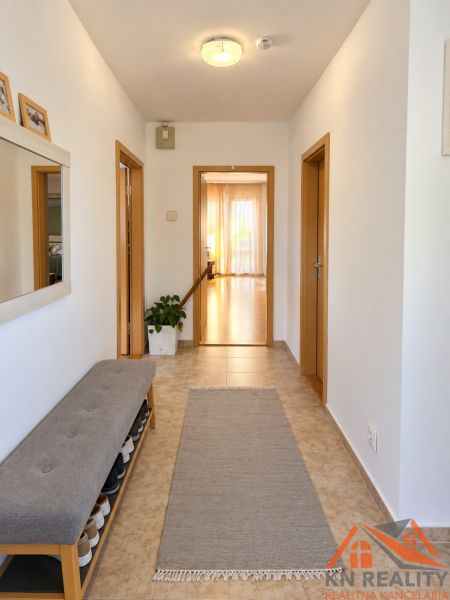 Flur in einem Einfamilienhaus mit Fliesen, einer Schuhbank und einem Spiegel.