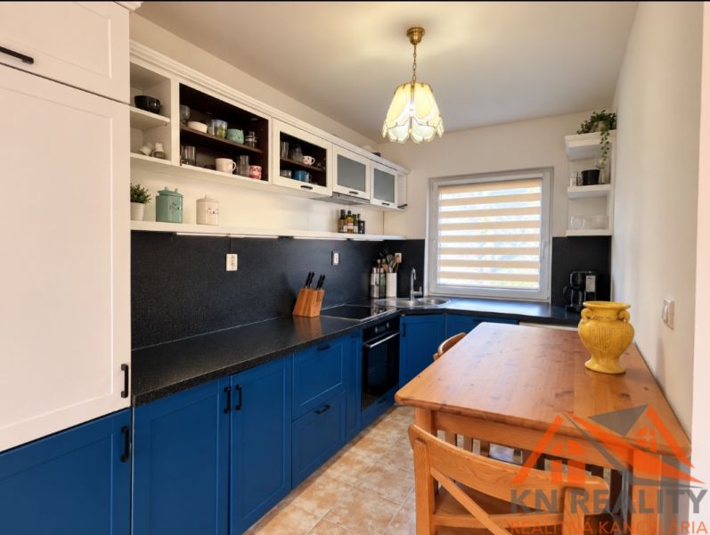 Eine Küche in einem Einfamilienhaus mit stilvollen blauen Schränken und einem gemütlichen Holztisch.