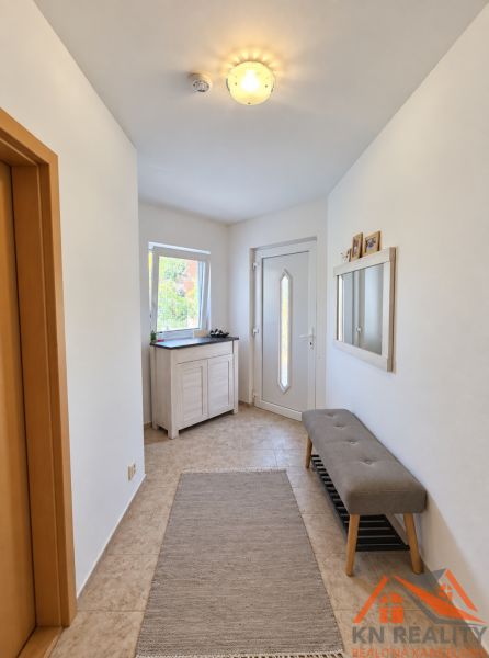 Ein heller Eingangsbereich in einem Einfamilienhaus mit einer Bank und einem Spiegel an der Wand.