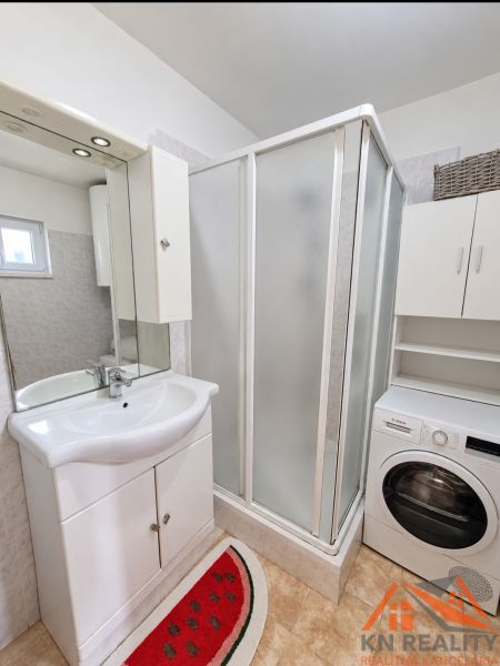 Badezimmer in einem Einfamilienhaus mit Waschbecken, Duschkabine und Waschmaschine.