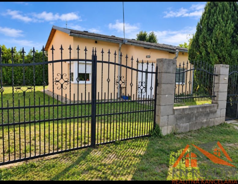 Ein Einfamilienhaus in Martovce mit einem Rasen-Grundstück und einem Metallzaun.