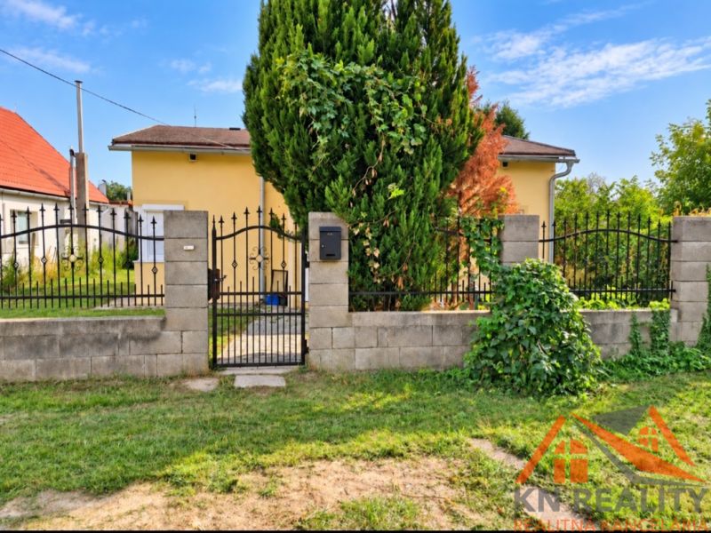 Ein Einfamilienhaus in Martovce mit einem Vorgarten und einem Metalltor, umgeben von einer Hecke.