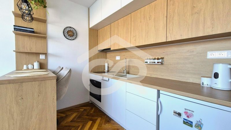 Küchenzeile in einem Einzimmerapartment mit Holzboden und eingebauten Geräten.