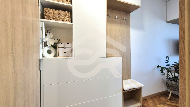 Innenraum eines Einzimmerapartments mit Holzmöbeln, Dekorationen und einer Pflanze auf dem Boden mit Holzdekor.