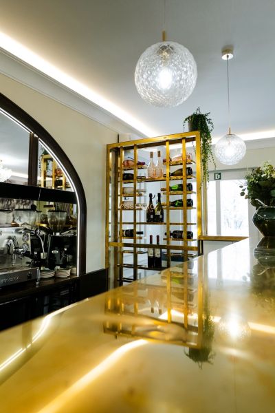 Eleganter Weinkeller und Bar in Geschäftsräumen mit moderner Beleuchtung und goldenen Details.