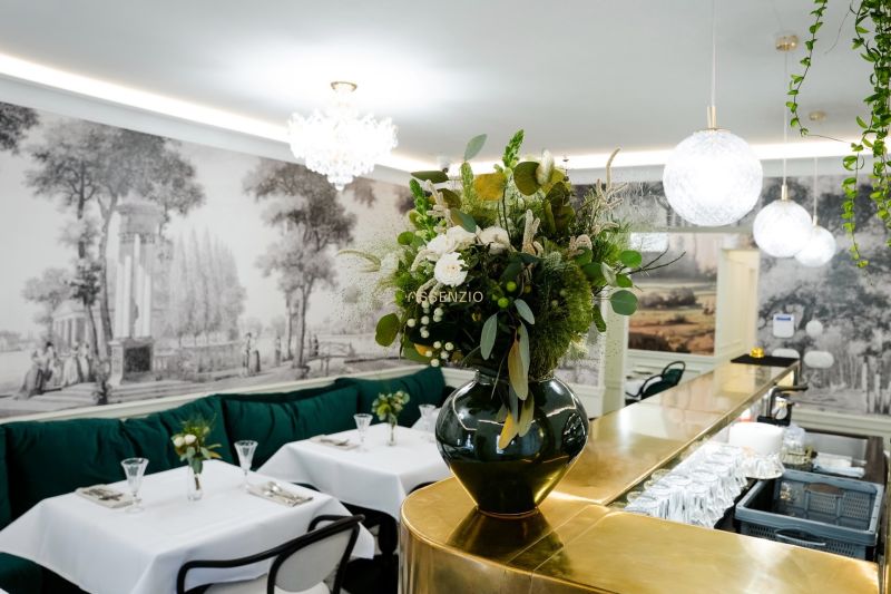 Innenraum von Geschäftsräumen mit goldener Bar, Blumendekoration und eleganten Tischen.