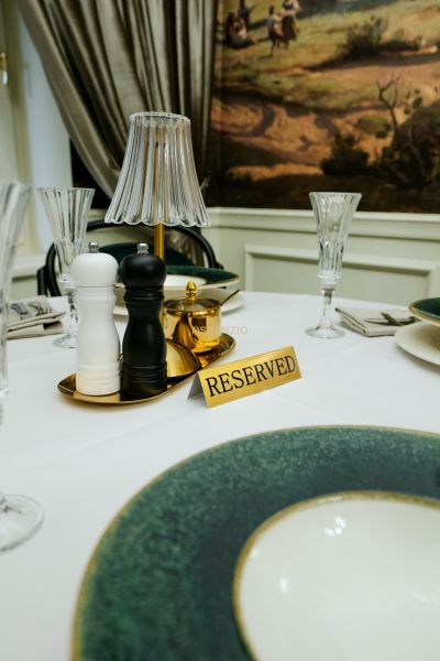 Ein reservierter Tisch mit Tischdecke in Geschäftsräumen, enthält Gewürzstreuer und elegante Gläser.