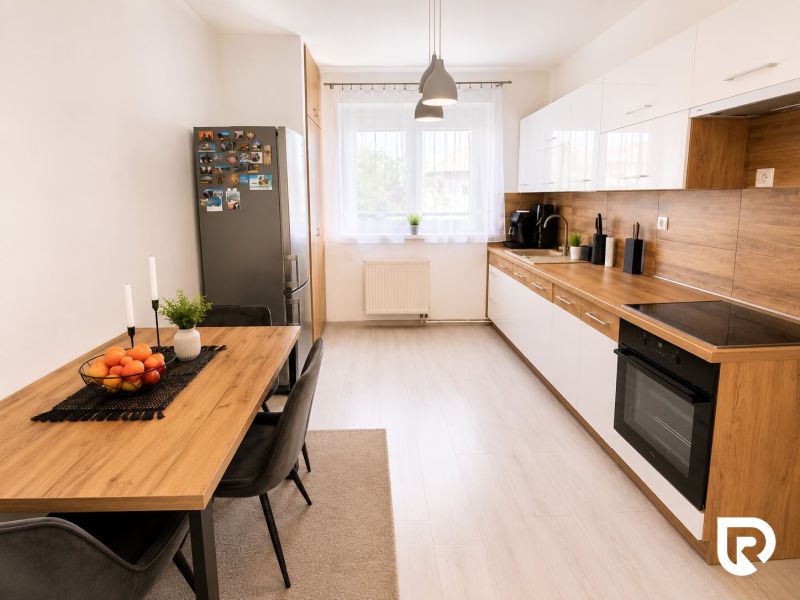 Küche in einer 2-Zimmer-Wohnung mit Holzboden, Esstisch und Geräten.