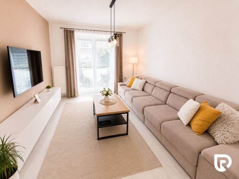 Helles Wohnzimmer in einer 2-Zimmer-Wohnung mit einem bequemen Sofa und Fenstern.
