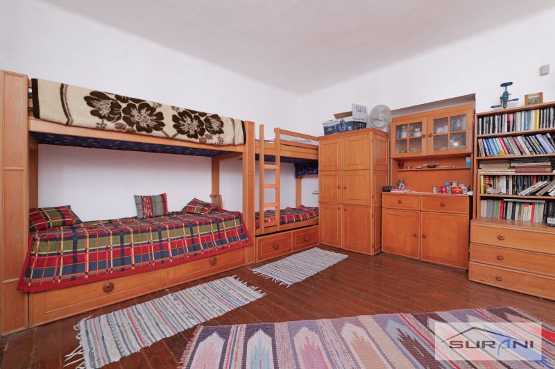 Innenraum eines Einfamilienhauses mit einem Etagenbett, Kommoden und einem Boden mit Holzdekor.