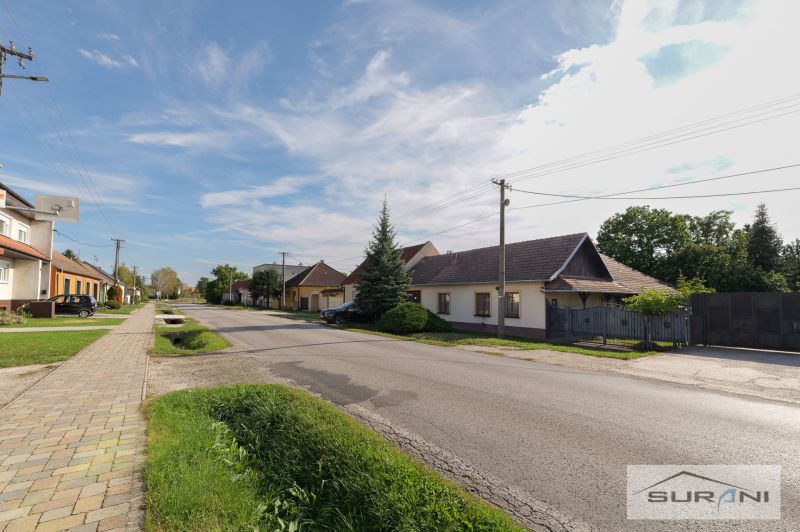 Einfamilienhäuser in der Hauptstraße in Štefanová mit gepflegtem Garten und klarem Himmel.