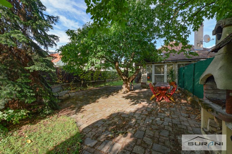 Im Garten des Einfamilienhauses in der Hauptstraße in Štefanová gibt es eine Sitzgelegenheit unter einem ausladenden Baum.