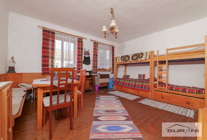 In einem Einfamilienhaus gibt es ein Etagenbett, einen Tisch und einen Boden mit Holzdekor.