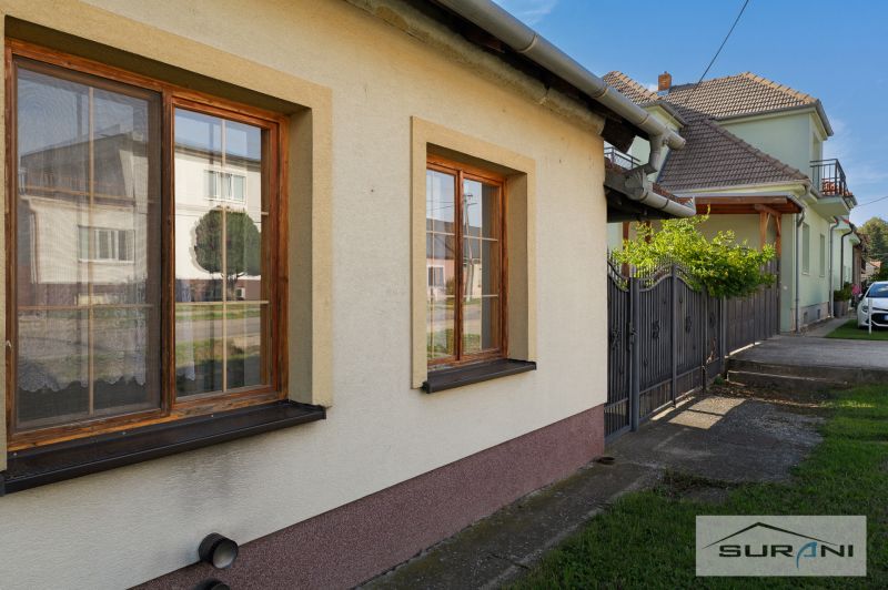 Ein Einfamilienhaus in der Hauptstraße in Štefanová mit braunen Fenstern und einem grünen Rasen.