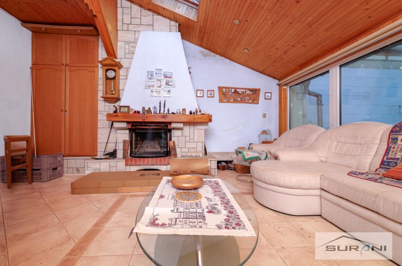 Wohnzimmer mit Kamin und Sofa in einem Einfamilienhaus, Boden mit Holzdekor.