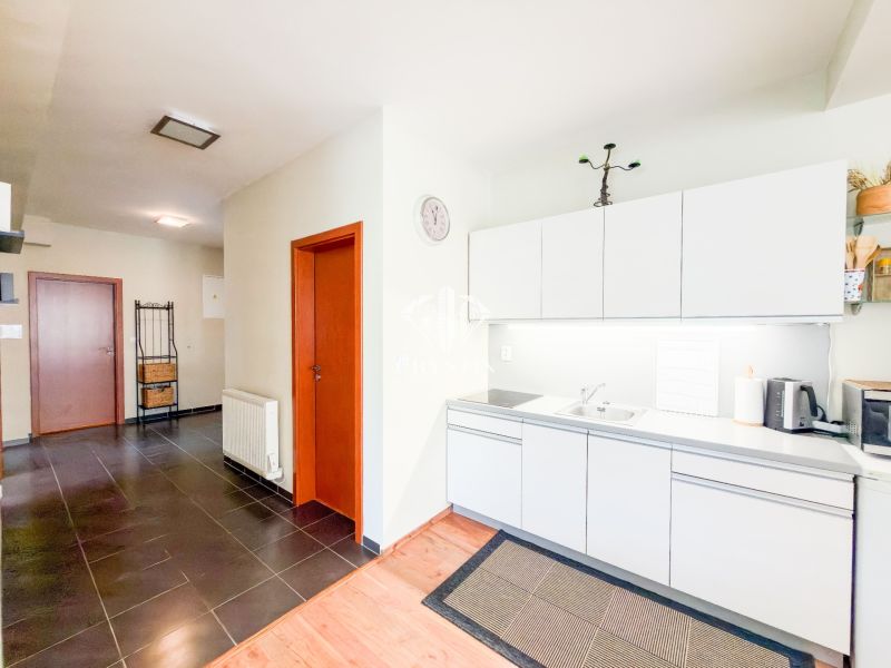 Küche in einer 3-Zimmer-Wohnung mit weißen Schränken und einem Boden in Holzoptik.