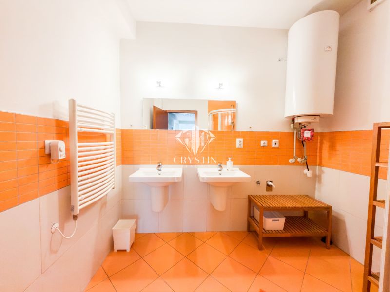 Badezimmer in einer 3-Zimmer-Wohnung mit orangefarbenen Fliesen, zwei Waschbecken und einem Boiler.