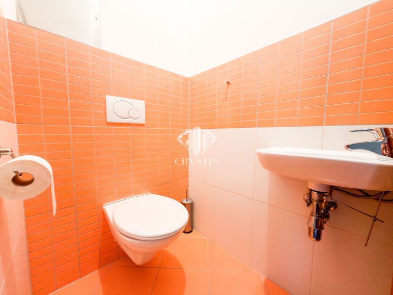 Badezimmer in einer 3-Zimmer-Wohnung mit orangefarbenen Fliesen und hängendem WC.