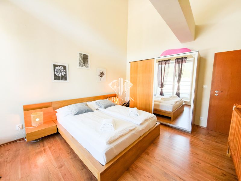 Schlafzimmer mit Bett und großem Schrank, auf einem Boden mit Holzdekor aufgebaut.