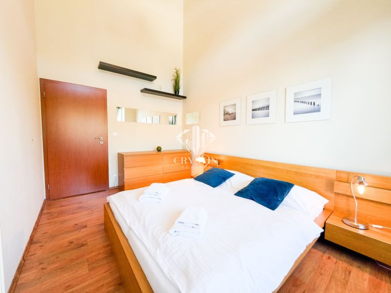 Schlafzimmer mit Holzboden, Bett, Kommode und Dekorationen in einer 3-Zimmer-Wohnung.