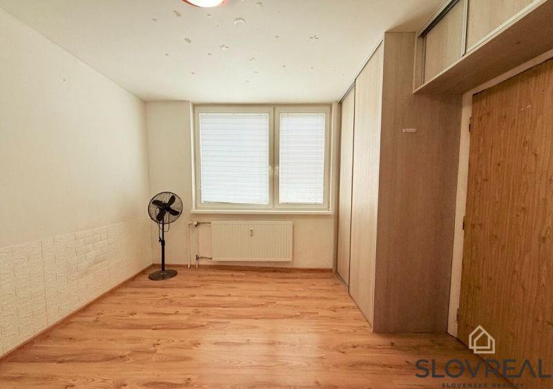 Ein Zimmer mit Holzboden, Ventilator und Stauraum in einer 3-Zimmer-Wohnung.
