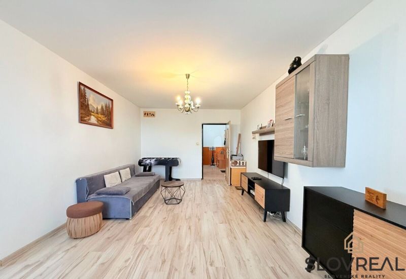 Wohnzimmer in einer 3-Zimmer-Wohnung mit Holzboden, grauem Sofa und Tischfußball.